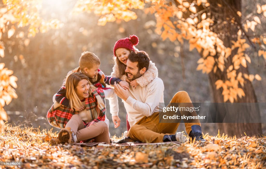Playful family having fun in autumn day at the park.