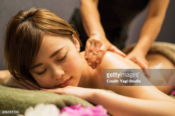 jonge vrouw ontvangen olie massage - spa behandeling stockfoto's en -beelden