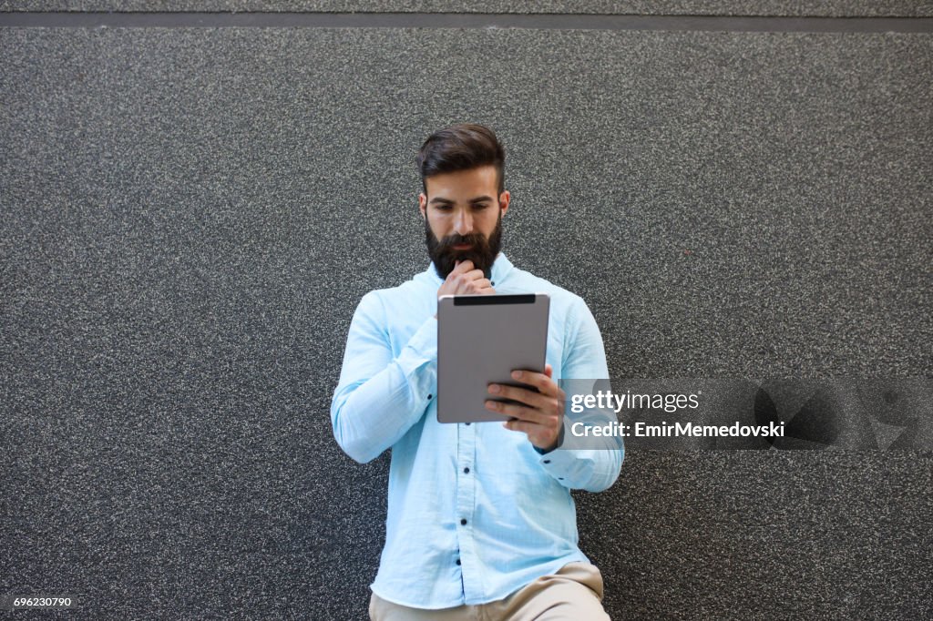 Stylish businessman using digital tablet outdoors