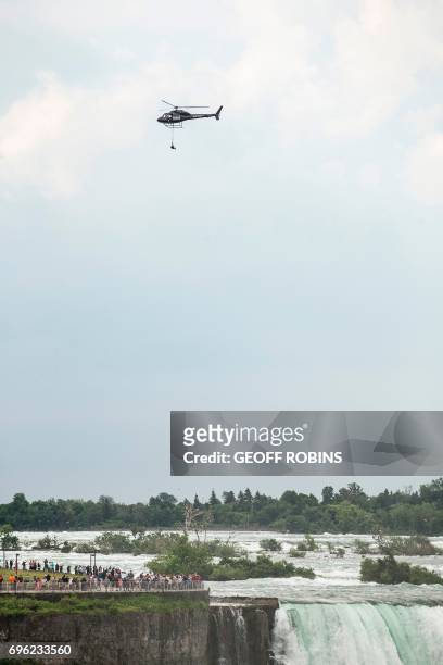 Aerialist Erendira Wallenda hangs beneath a helicopter during a stunt over the Horseshoe Falls at Niagara Falls, New York, June 15, 2017. / AFP PHOTO...
