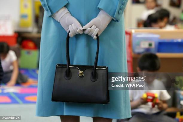 Britain's Queen Elizabeth II holds her handbag as she tours the classrooms at Mayflower Primary School during a visit to Poplar in Tower Hamlets on...