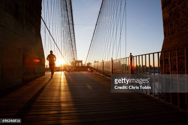 silhouette of jogger on brooklyn bridge at sunset - street style new york stock pictures, royalty-free photos & images