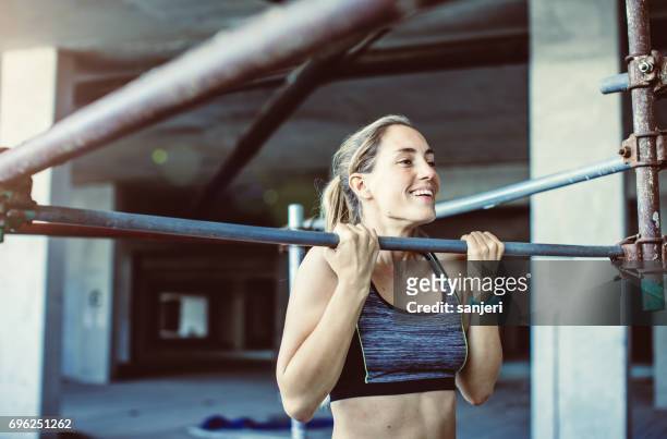 young woman exercising pull-ups - pull ups stock pictures, royalty-free photos & images