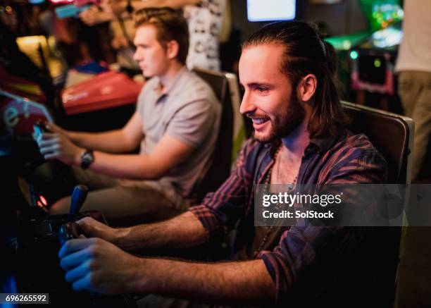 playing arcade driving games - amusement arcade stock pictures, royalty-free photos & images