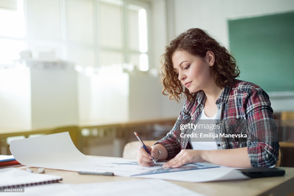 Young female architect working at a drawing board