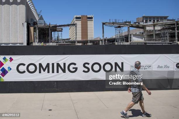 Pedestrian walks past a "Coming Soon" sign displayed outside of a building under construction in Sacramento, California, U.S., on Tuesday, June 6,...