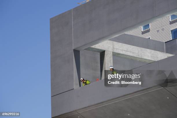 Workers look over the edge of a building under construction in Sacramento, California, U.S., on Tuesday, June 6, 2017. As the cost of daily life...