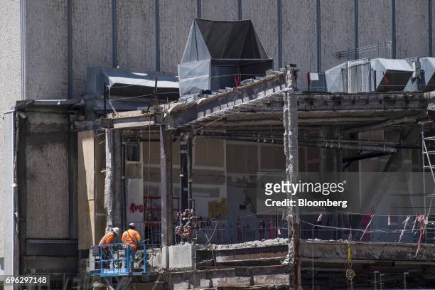 Workers stand on a cherry picker next to a building under construction in Sacramento, California, U.S., on Tuesday, June 6, 2017. As the cost of...