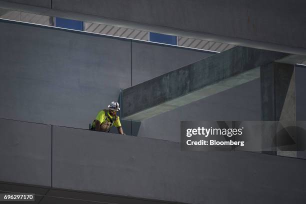 Worker looks over the edge of a building under construction in Sacramento, California, U.S., on Tuesday, June 6, 2017. As the cost of daily life...