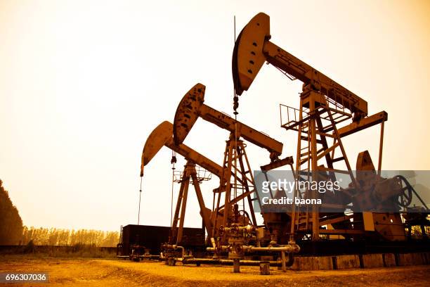 oliepompen werken bij zonsondergang - working oil pumps stockfoto's en -beelden