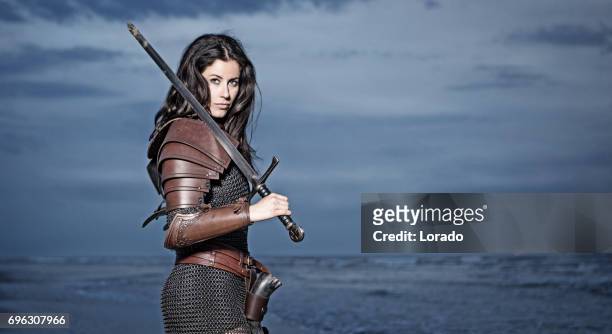 mujer de viking de pelo oscuro en el mar al atardecer - armoured fotografías e imágenes de stock