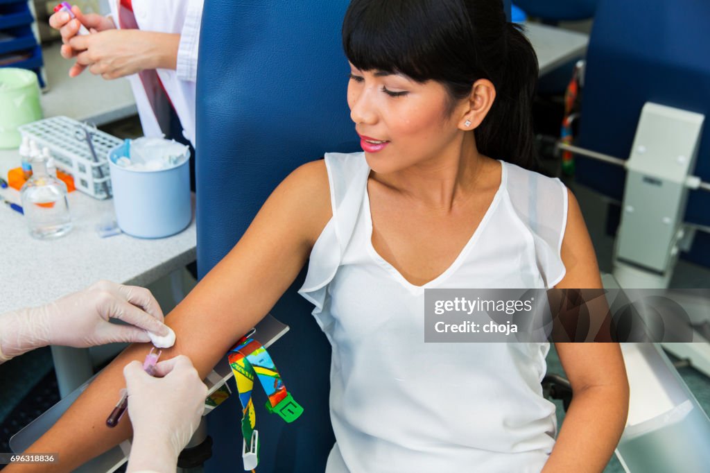 Drawing blood...nurse prepairing for blood capture from a vein for laboratory analyses from cute young woman