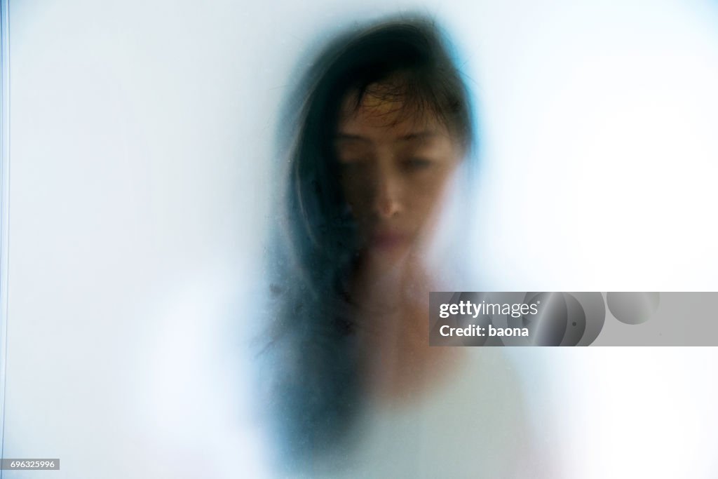 Kvinna ansikte peering genom frostat glas