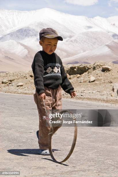 Boy playing with a basic toy made out of a piece of wire and a metallic ring.