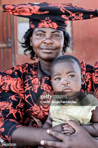 Portrait of a Herero mother with the traditional Herero headwear holding her child.