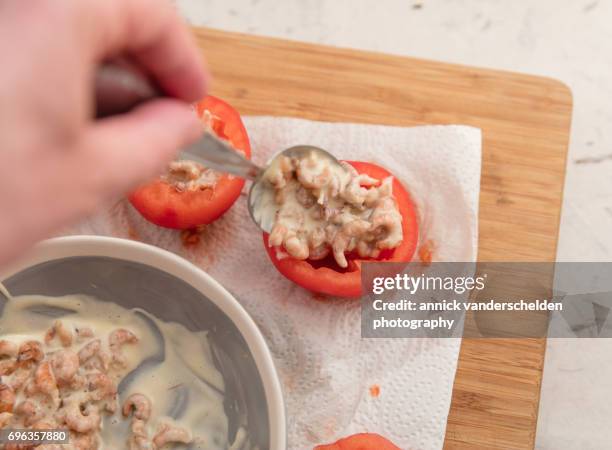 filling hollowed-out tomatoes with shrimp mixture. - shrimps stock pictures, royalty-free photos & images