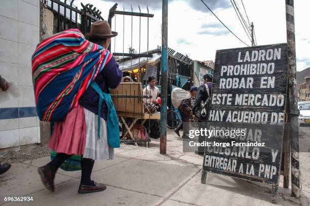 Indigenous woman entering a street market with a sign warning thiefs.