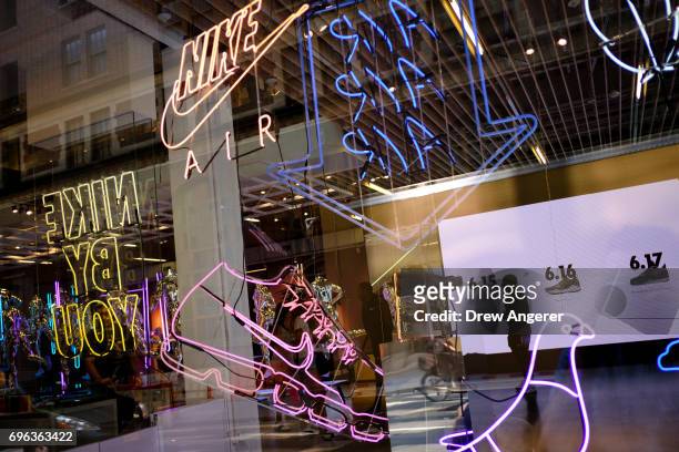 Seen through a store window, a Nike employee stands in the entryway of the Nike SoHo store, June 15, 2017 in New York City. Nike announced plans on...