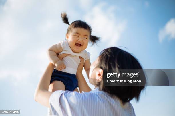 women lifting up baby girl - korean baby girl stock-fotos und bilder