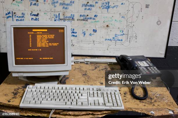messy and worn office desk in manufacturing facility - old monitor computer stock-fotos und bilder