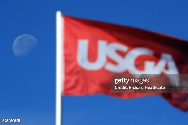 The moon is seen next to a flag during a practice round prior to the 2017 U.S. Open at Erin Hills on June 14, 2017 in Hartford, Wisconsin. Photo by...