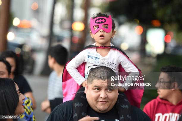 Natalya Rosas sits on the shoulders of her father Ernesto Rosas as they wait to see the Batman "Bat-signal" projected onto Los Angeles City Hall in a...