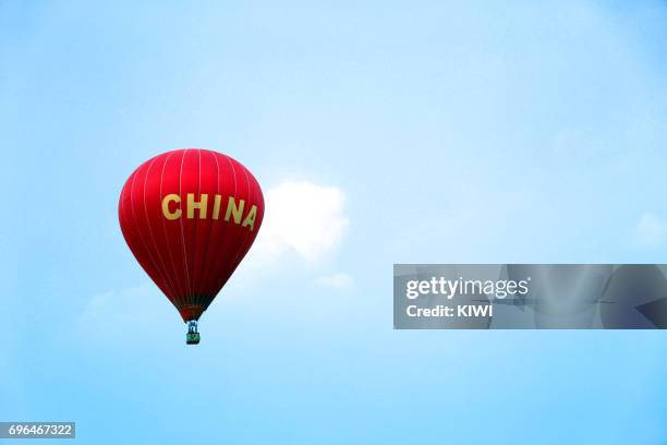 the red hot air balloon is flying on the blue sky - flying kiwi stock pictures, royalty-free photos & images