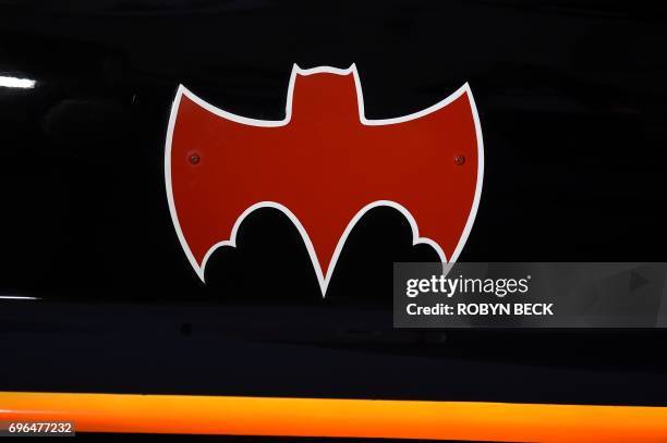 Fans gather around a Batmobile before a tribute to "Batman" star Adam West that includes lighting a Bat-signal at City Hall, June 15 in Los Angeles,...