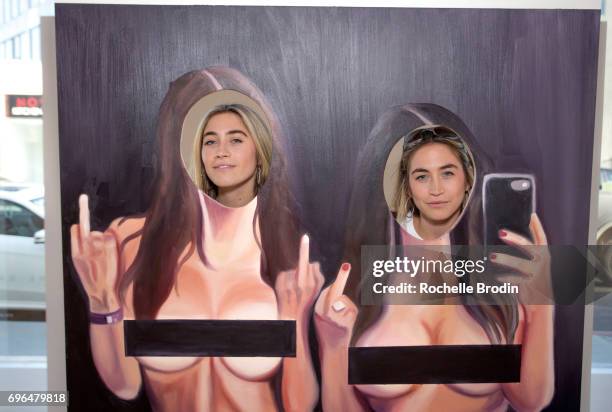 Allie Kaplan and Lexi Kaplan pose with their installation during the "Make Me Famous" exhibit hosted by The Kaplan Twins at De Re Gallery on June 15,...