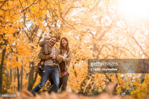 famiglia spensierata che si diverte mentre corre nel parco. - autunno foto e immagini stock