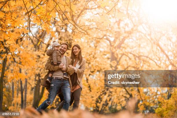 carefree family having fun while running in the park. - autumn family stock pictures, royalty-free photos & images