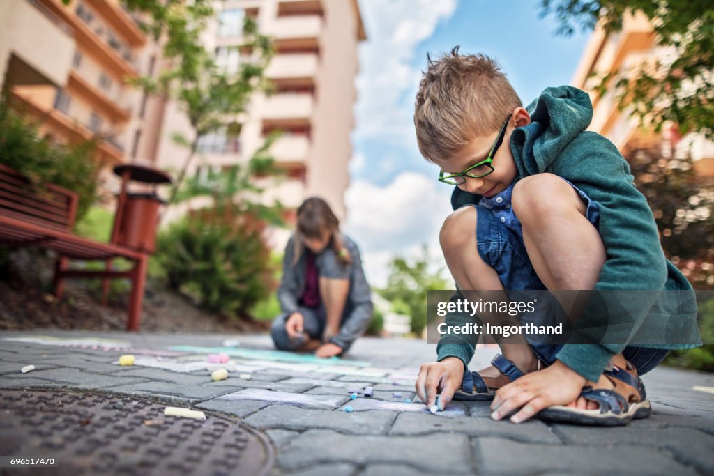 Kids drawing with chalk on sidewalk in residential area