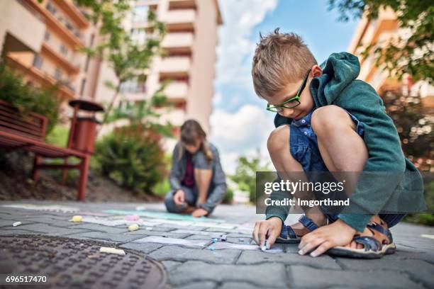 kids drawing with chalk on sidewalk in residential area - modern apartment building exterior stock pictures, royalty-free photos & images