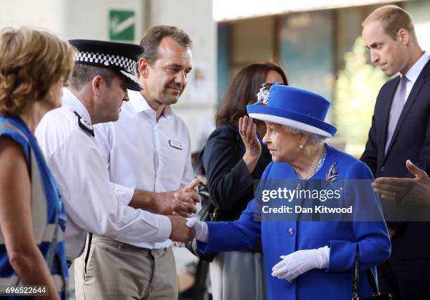 Queen Elizabeth II and Prince William, Duke of Cambridge greet members of emergency services at the scene of the Grenfell Tower fire on June 16, 2017...