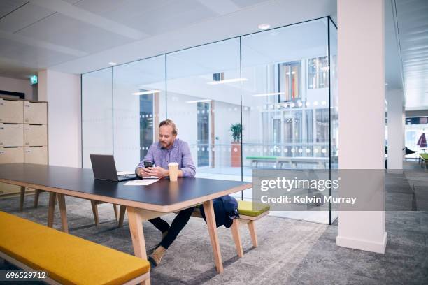 creative businessman texting on cell phone in conference room - bank meeting stock-fotos und bilder