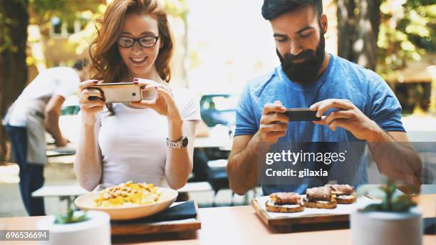 una coppia che scatta foto di cibo. - coppie cibo food bistrot foto e immagini stock