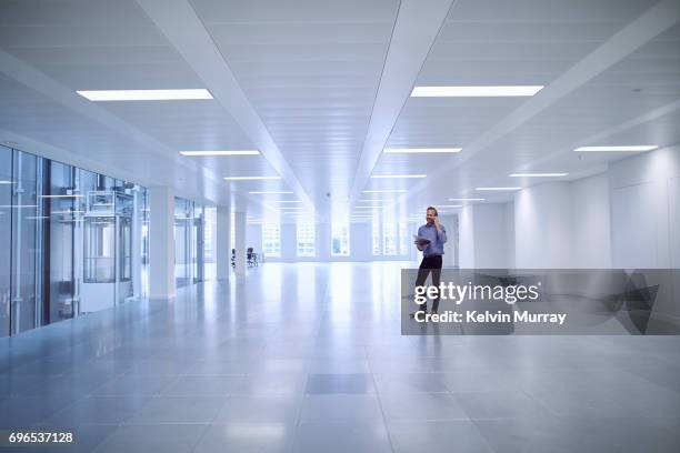 architect using cell phone in empty office - ceiling light photos et images de collection