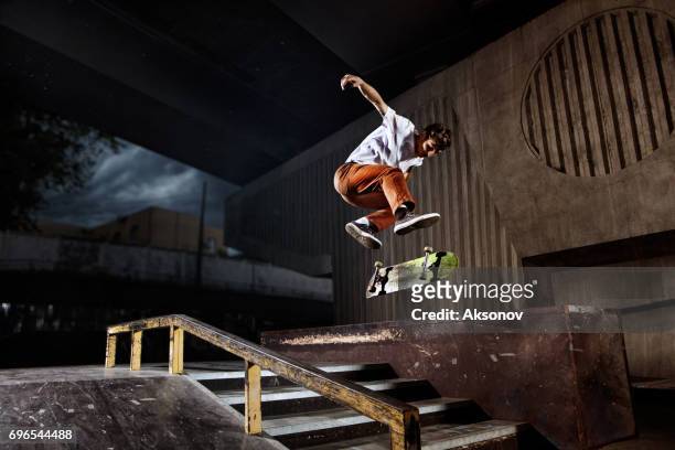 skater springen auf seinen skate im skatepark - skate stock-fotos und bilder