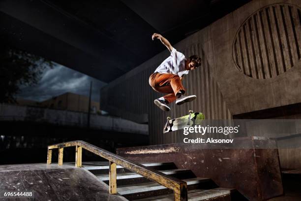 skater saltando sobre su skate en el skatepark - monopatín artículos deportivos fotografías e imágenes de stock