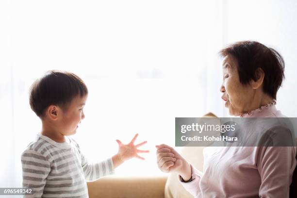 senior woman and boy playing at home together - rock paper scissors stock pictures, royalty-free photos & images