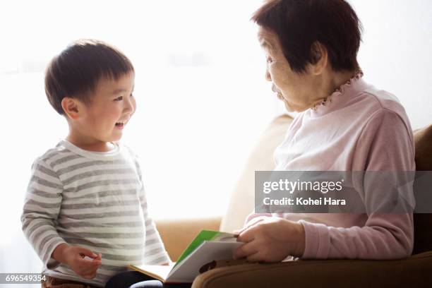 senior woman and boy reading a book together - first grandchild stock pictures, royalty-free photos & images