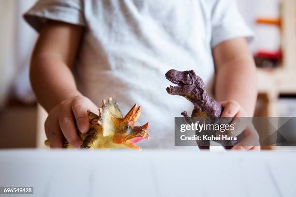 hands of boy playing with miniature scale dinosaurs - child toy photos et images de collection