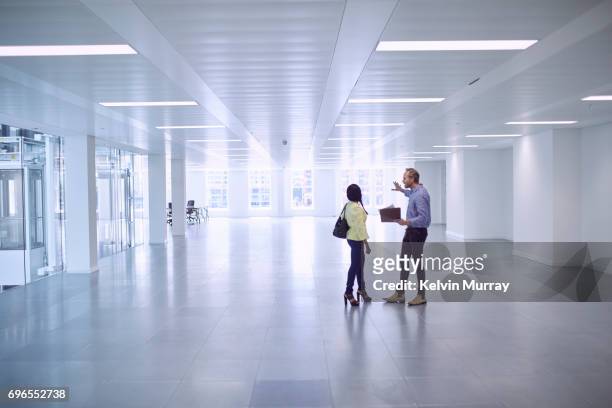 architect discussing project with colleague in empty office - moving office stock pictures, royalty-free photos & images
