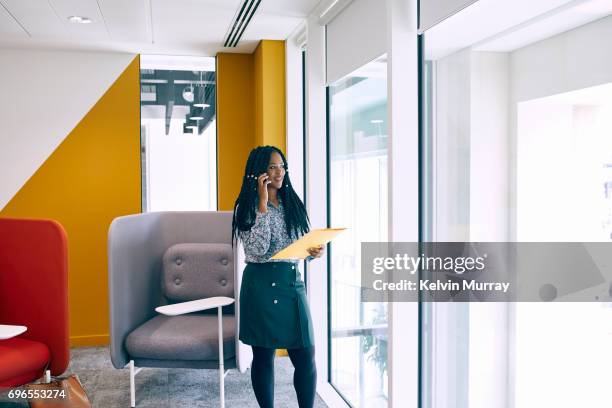 businesswoman using cell phone in creative office - yellow blouse stockfoto's en -beelden