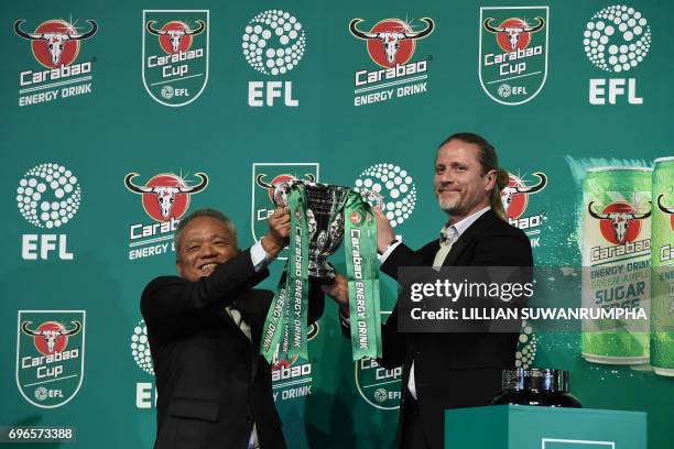 Of Carabao Group Sathien Setthasit and former French international footballer Emmanuel Petit raise the EFL Carabao Cup after the first draw for the...