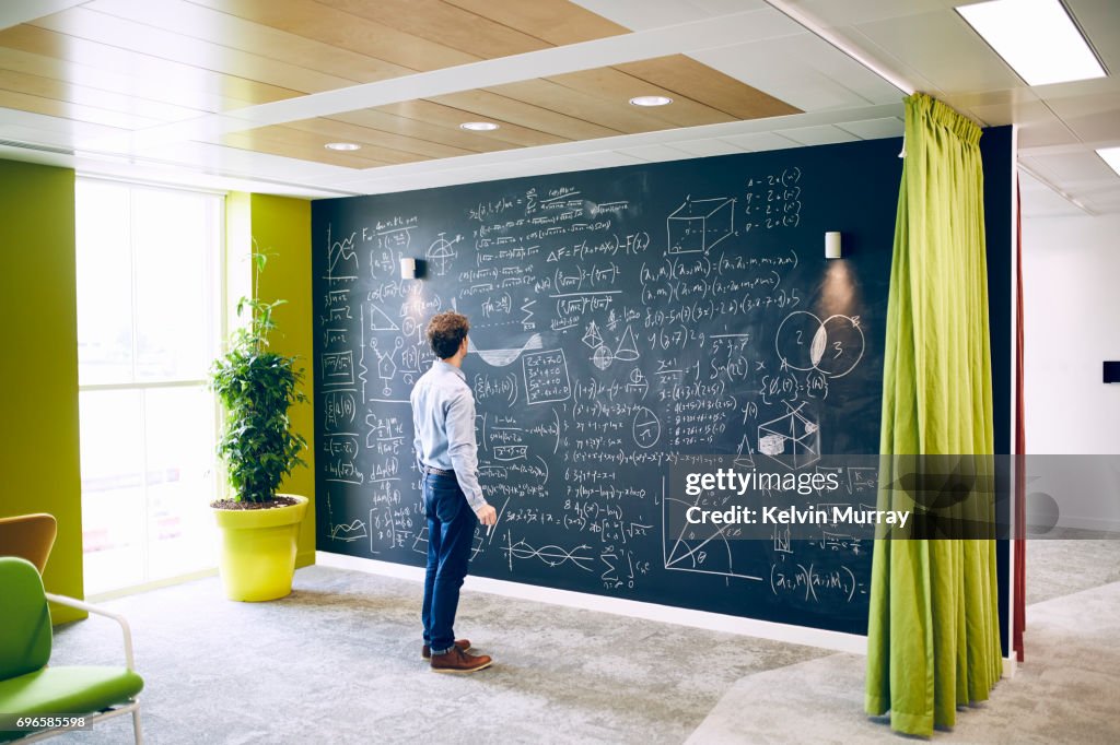 Businessman working with formula on wall