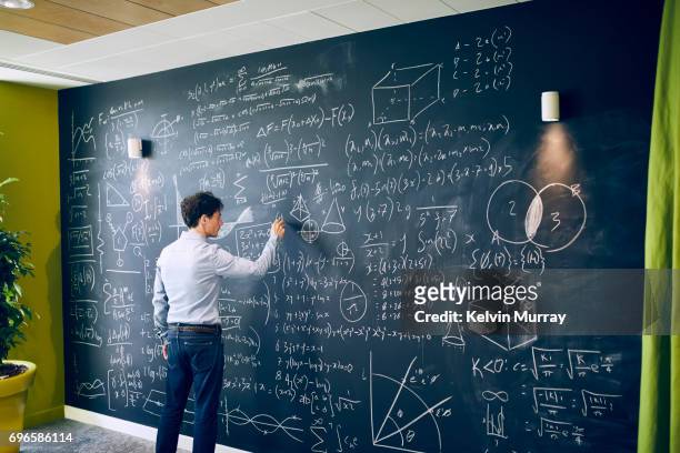 businessman working with formula on wall - ingewikkeldheid stockfoto's en -beelden