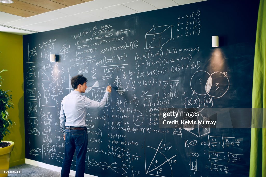 Businessman working with formula on wall