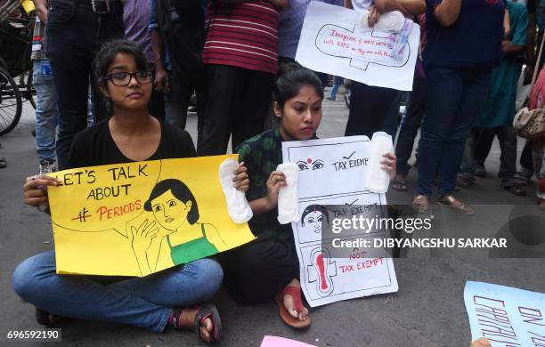 Indian students hold posters and sanitary napkins during a protest over a 12 per-cent tax on sanitary pads as part of the Goods and Services Tax in...