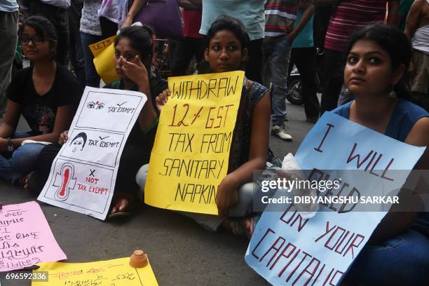 Indian students hold posters and sanitary napkins during a protest over a 12 per-cent tax on sanitary pads as part of the Goods and Services Tax in...